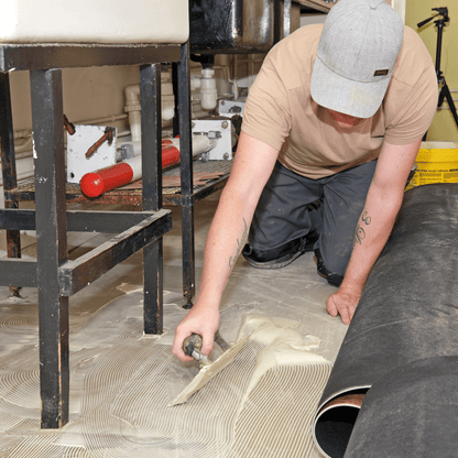 Vinyl floorcovering being fitted into Styccobond F44 adhesive