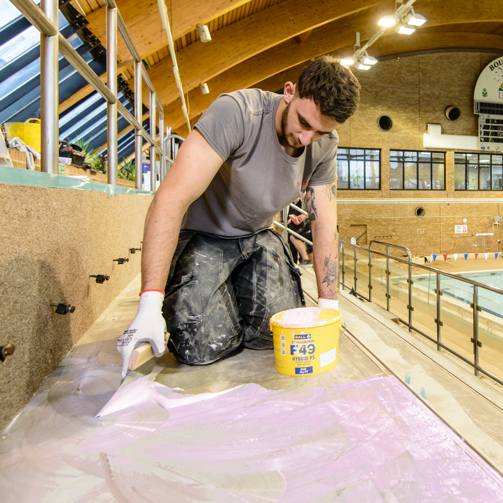Styccobond F49 Hybrid PS adhesive being applied on a poolside installation